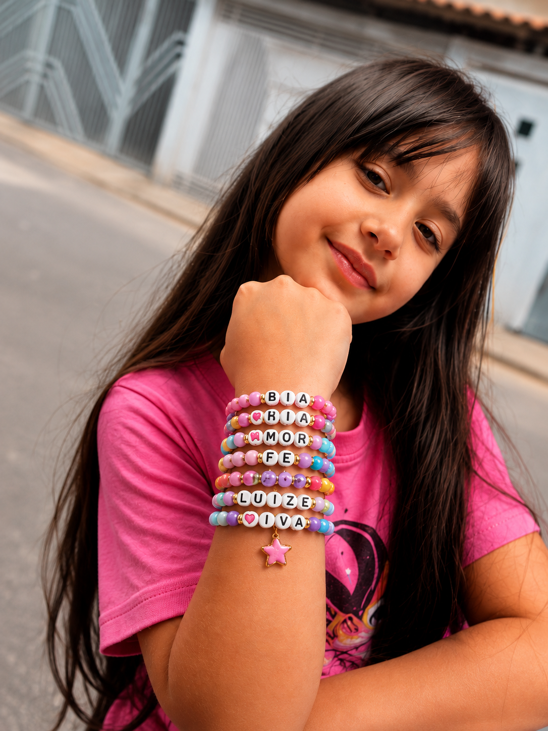 Beatriz sorrindo mostrando as pulseiras de elástico coloridas no braço